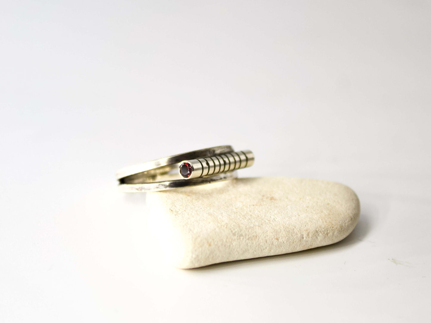 Anello Glimoire in argento con design a spirale e dettaglio con pietra rossa su base di pietra bianca