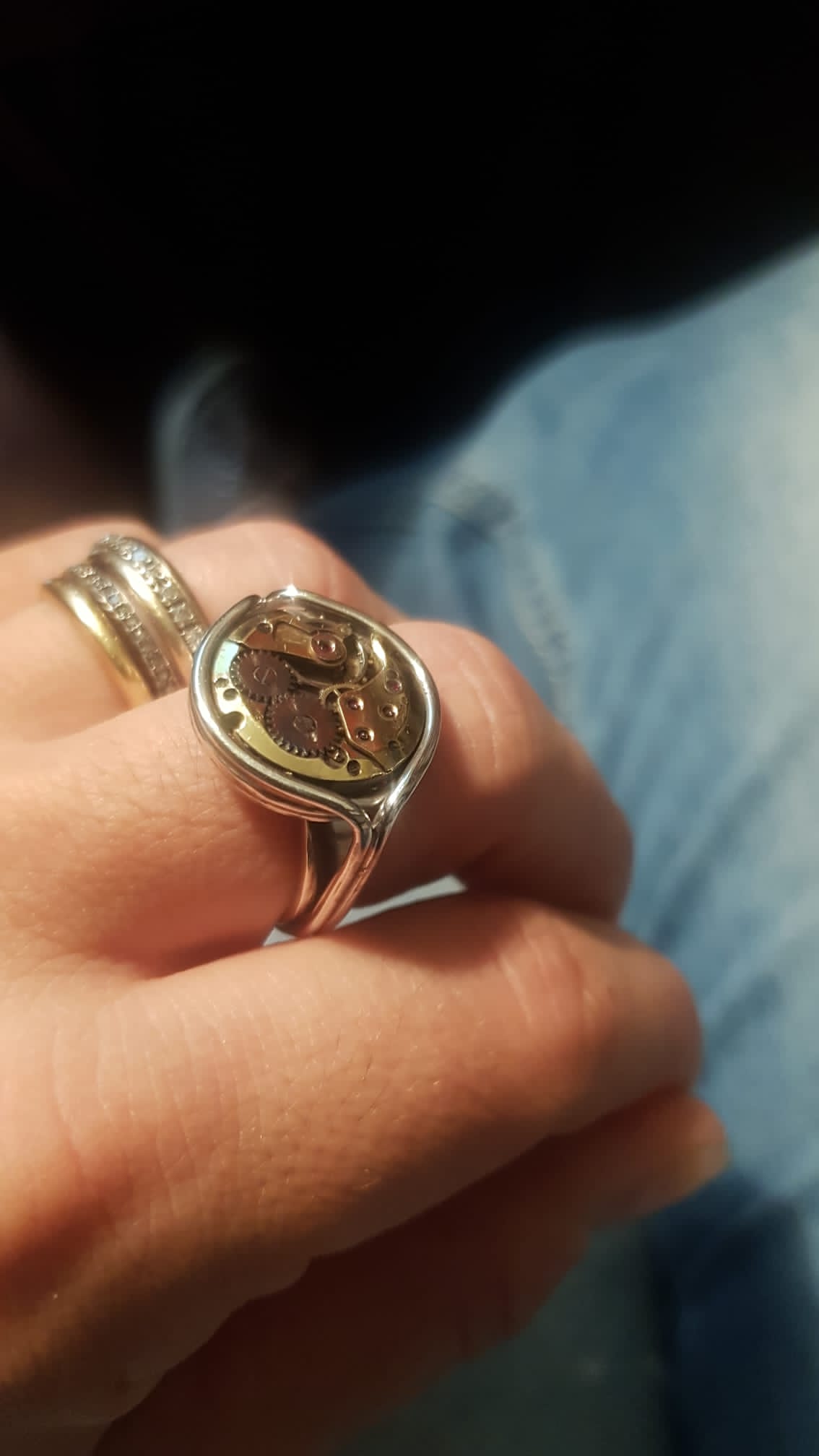 Anello con meccanismo di orologio Glimoire in metallo indossato su una mano maschile