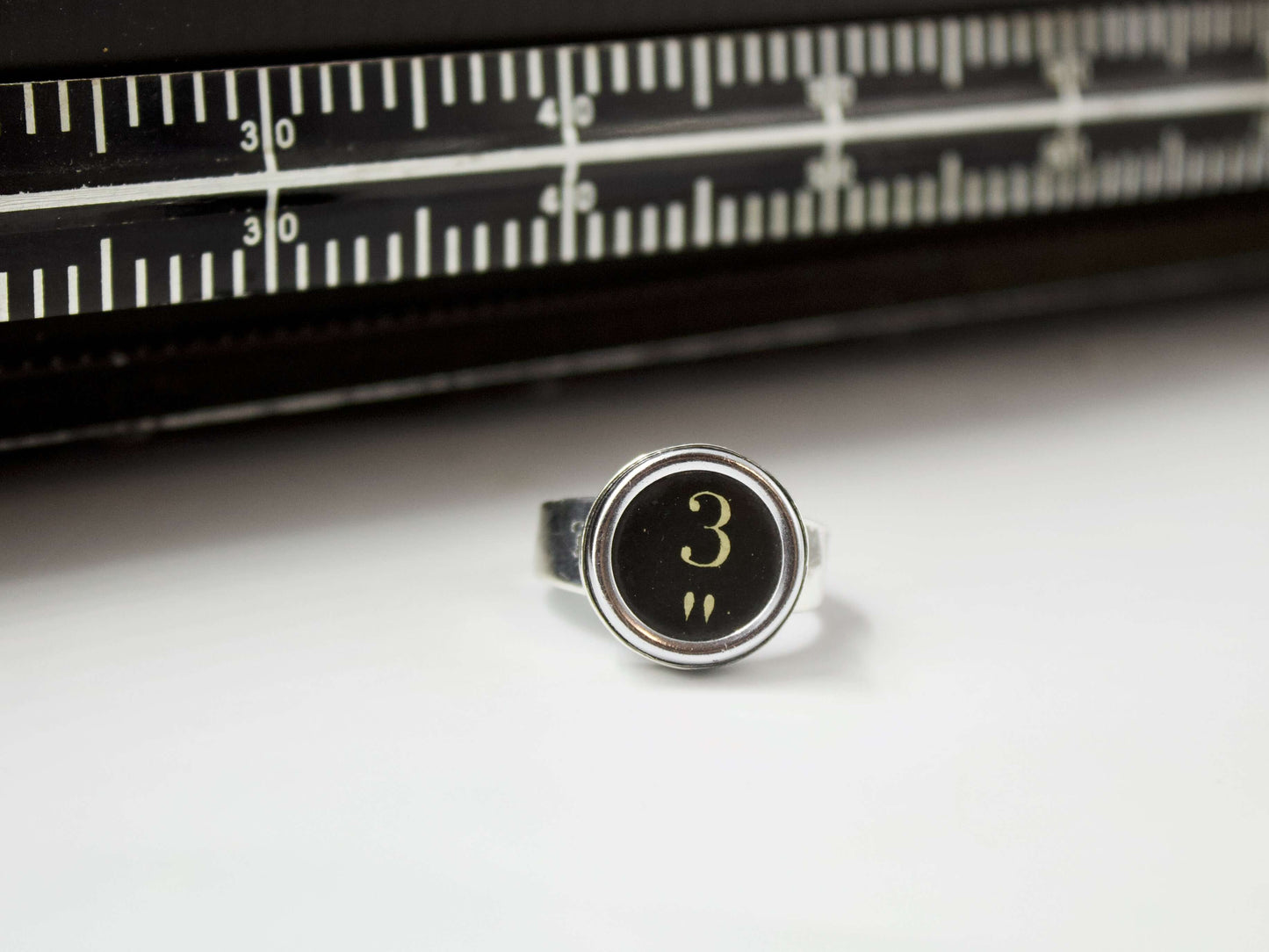Anello in argento con tasti di macchina da scrivere vintage numero 3 su sfondo bianco