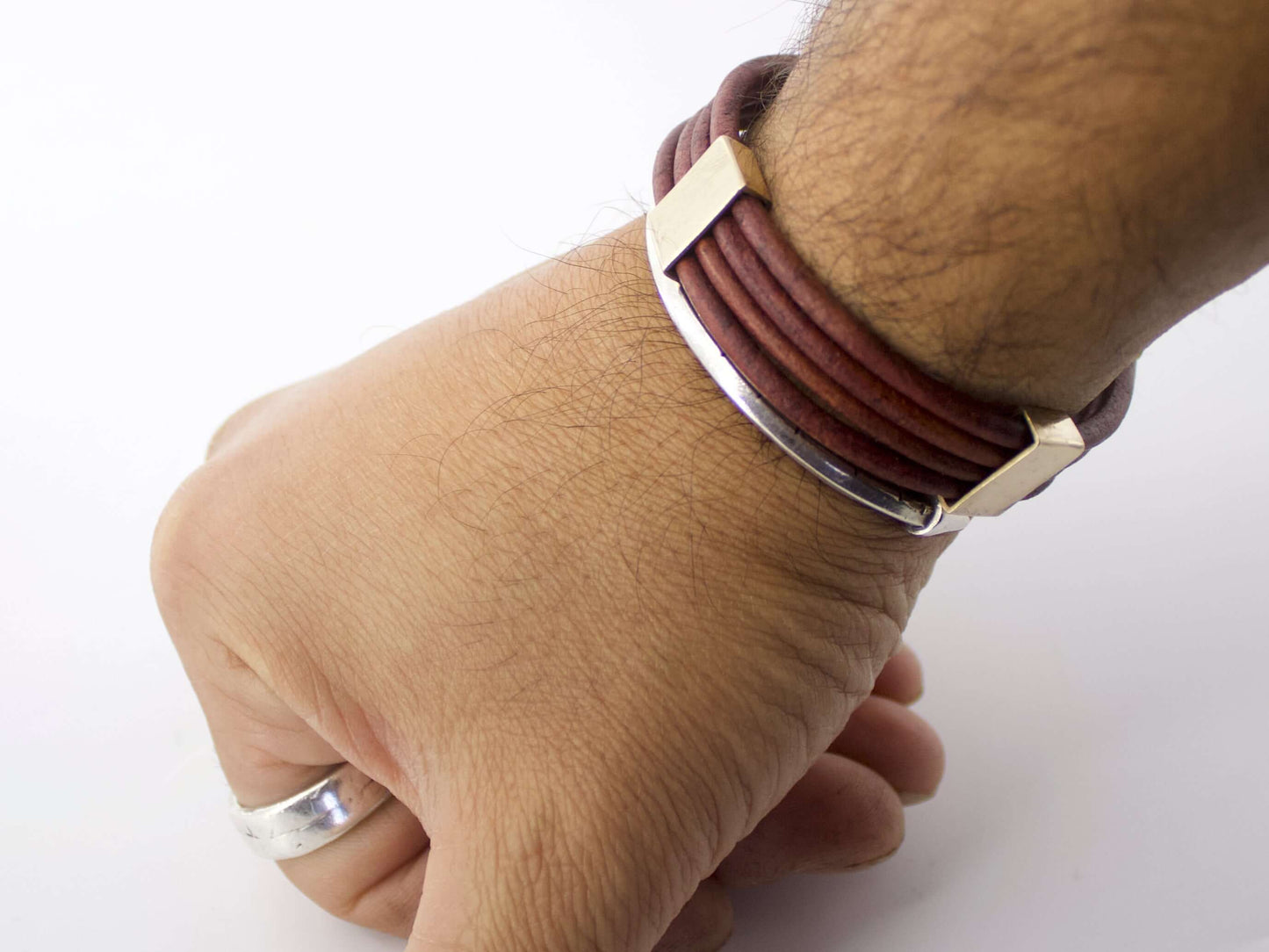 Bracciale maschile in cuoio marrone con dettagli metallici indossato al polso uomo