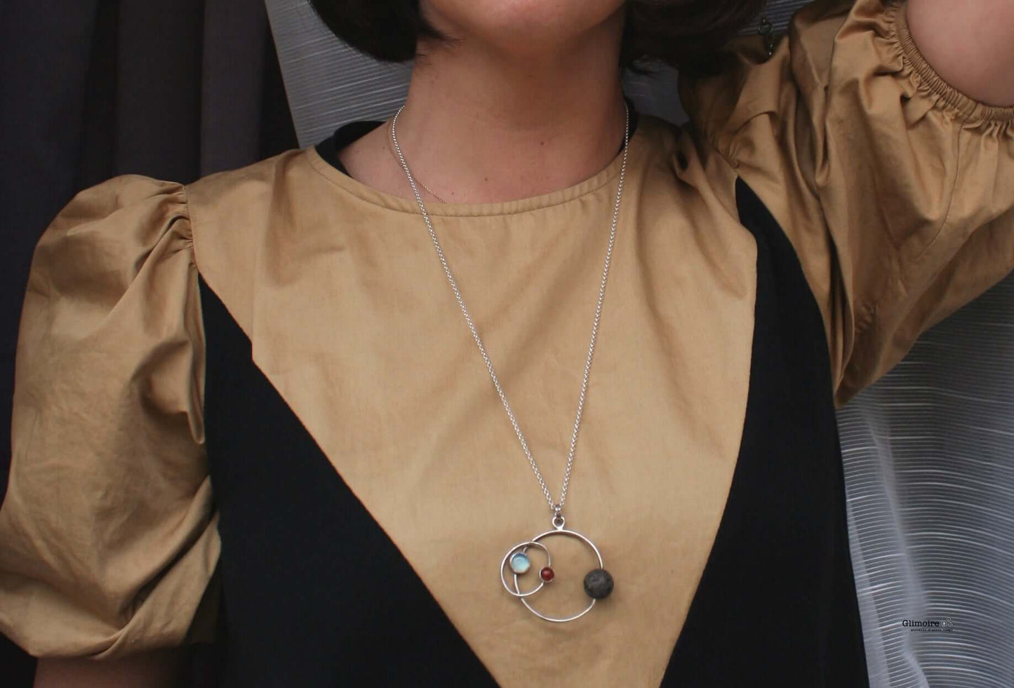 Collana Glimoire con pendente cerchi e pietre colorate indossata su abito beige e nero