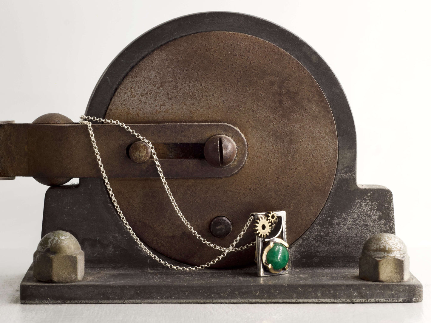 Collana Glimoire con pendente ingranaggi pietra verde su sfondo meccanico vintage