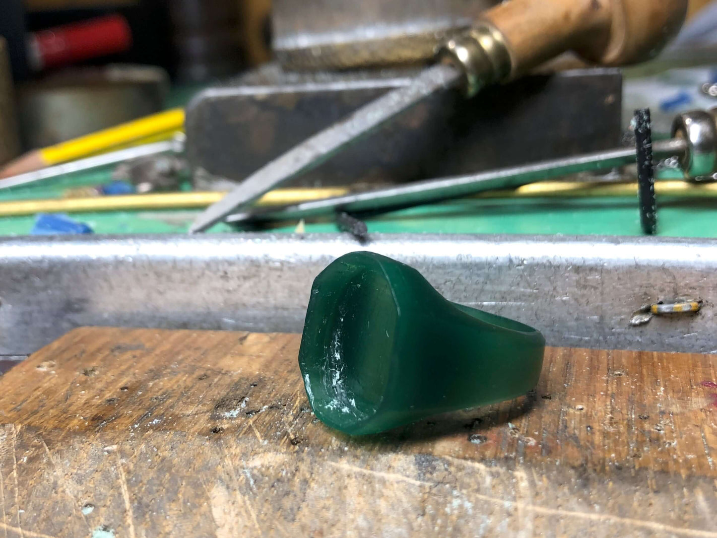 Anello modello in cera verde per creazione di gioielli artigianali Glimoire su banco da lavoro
