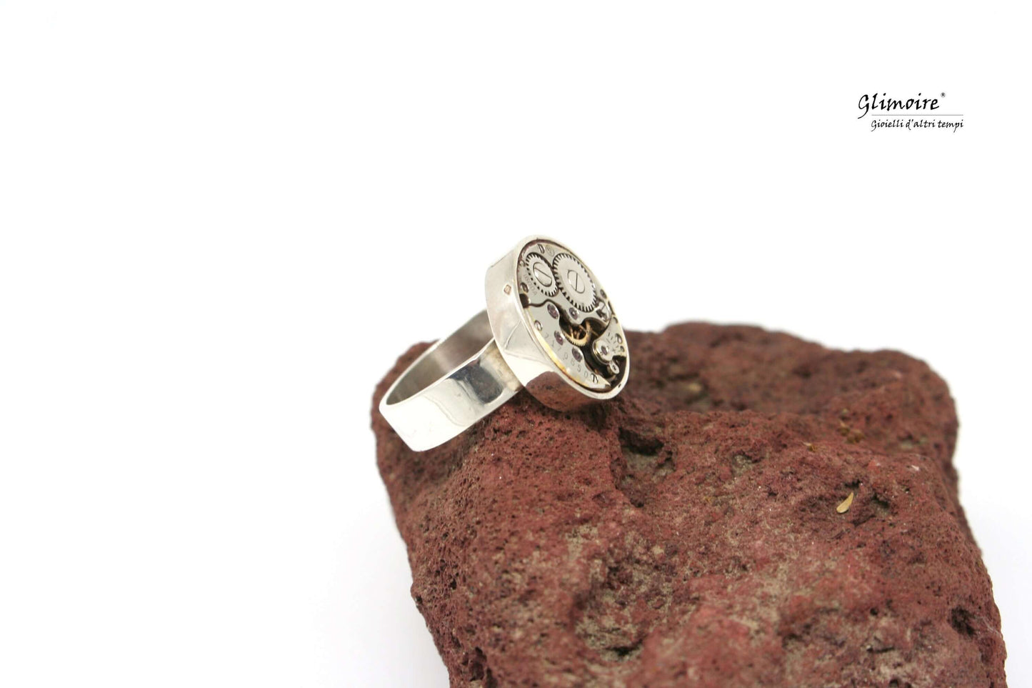 Anello con meccanismo di orologio in argento Glimoire su superficie di pietra rustica