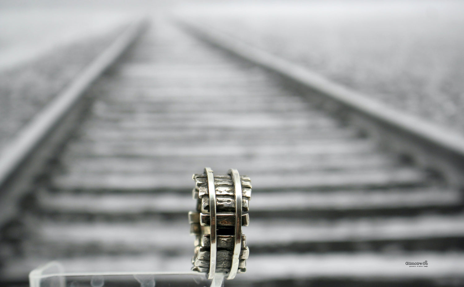 Gioielli ispirati ai treni Collezione di anelli e pendenti con ruote ferroviarie in metallo su binari sfocati