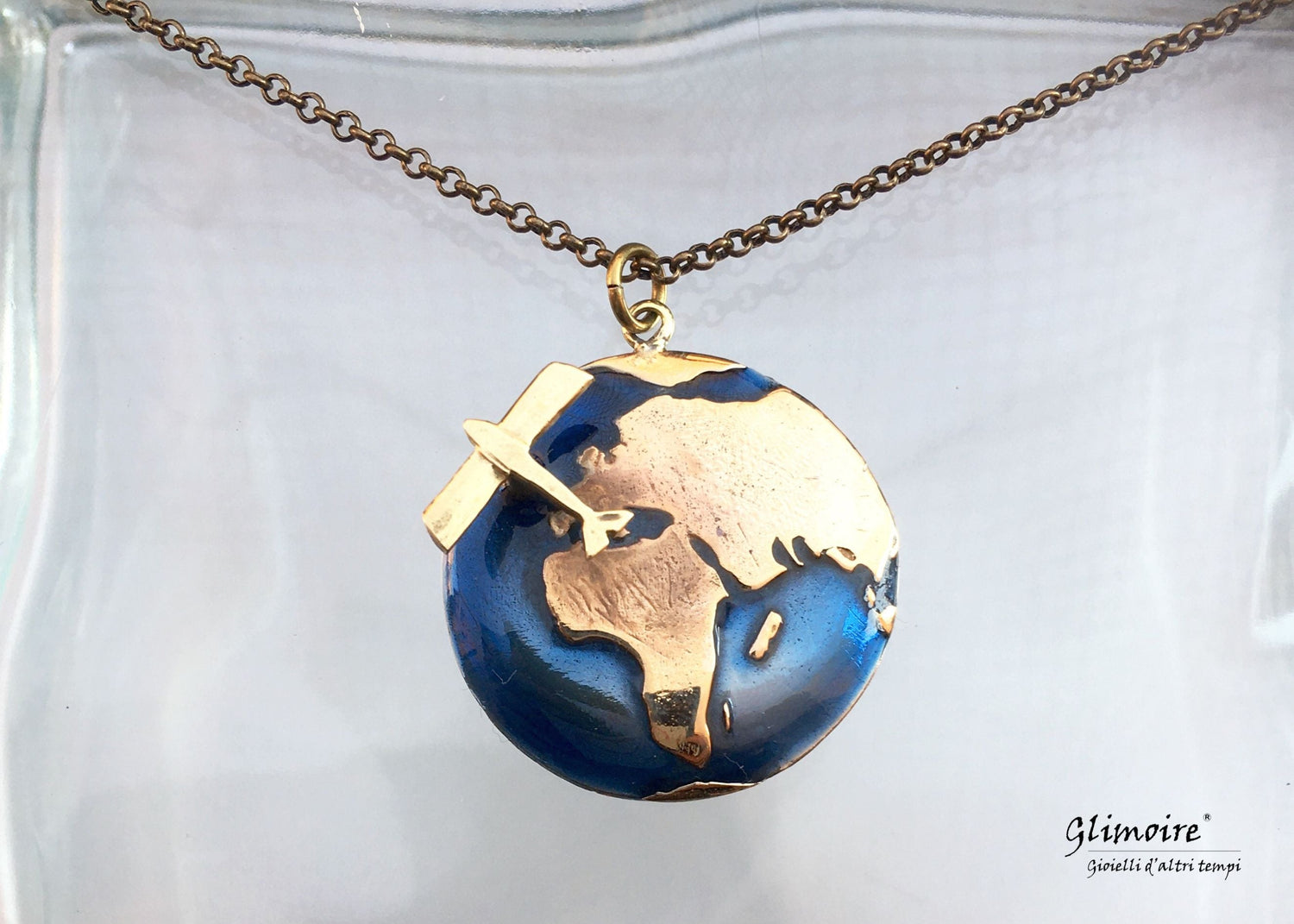 Collezione di gioielli su sfondo blu mare con pendente rettangolare in argento raffigurante una balena e catena sottile