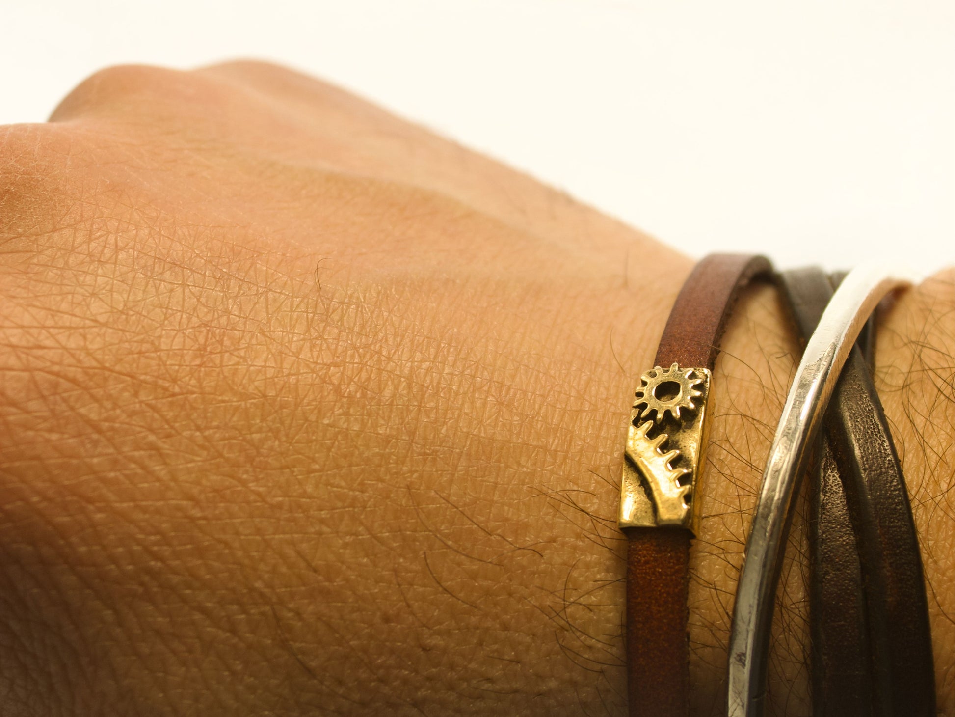 Bracciale industrial con ingranaggi in cuoio e bronzo indossato su un polso maschile