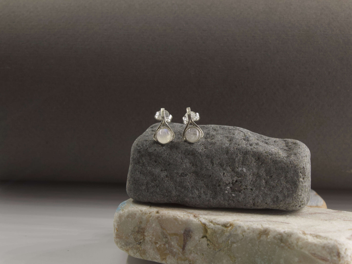 Orecchini a goccia con pietre colorate di Glimoire su una pietra grigia