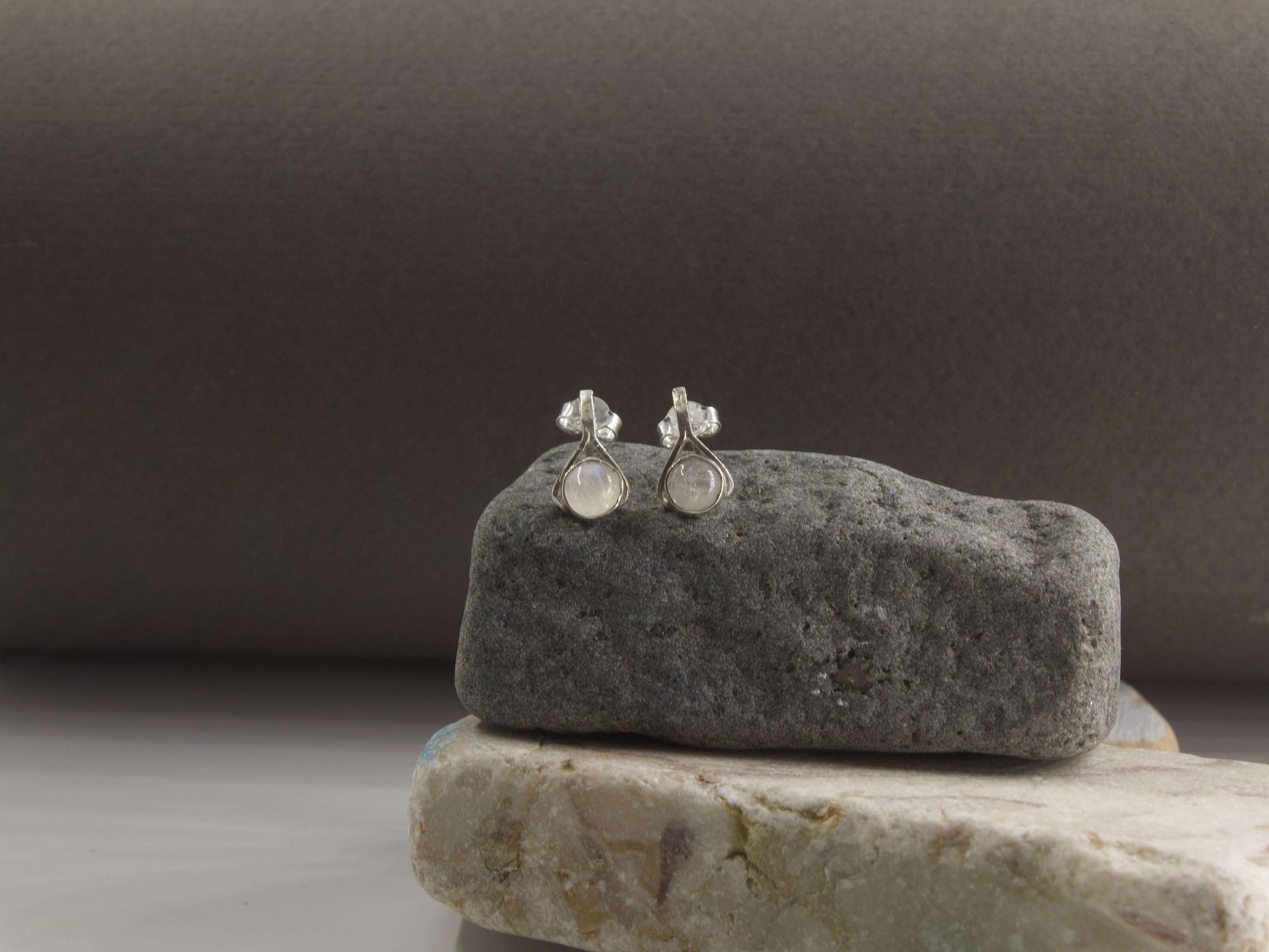 Orecchini a goccia con pietre colorate di Glimoire su una pietra grigia