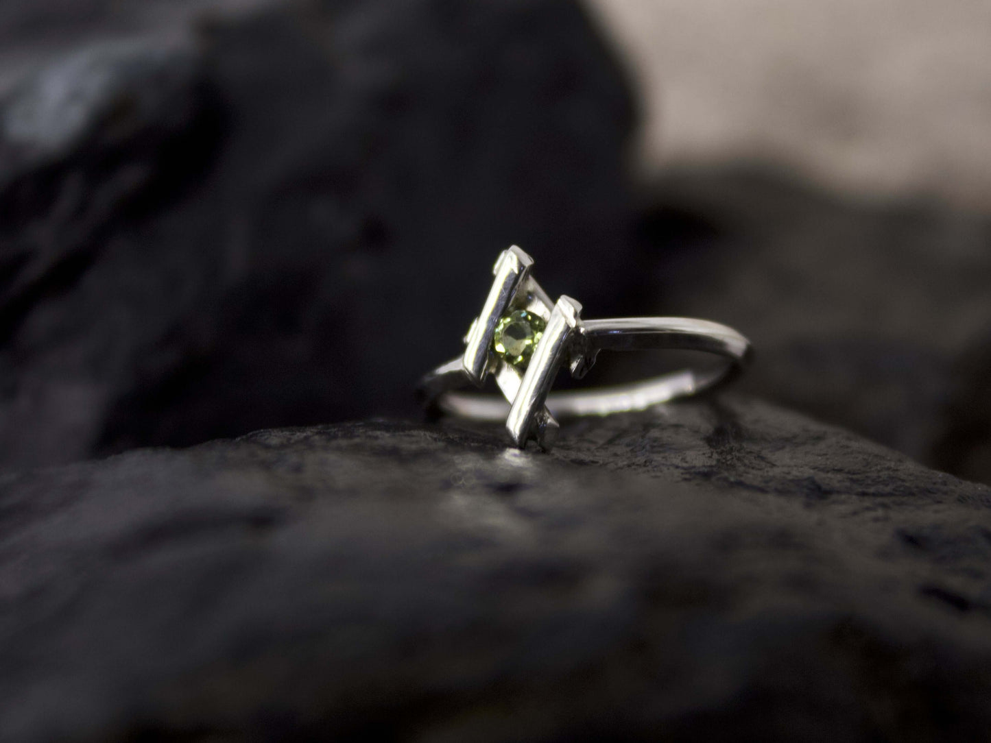 Elegante anellino in argento con pietra verde di Glimoire su sfondo scuro