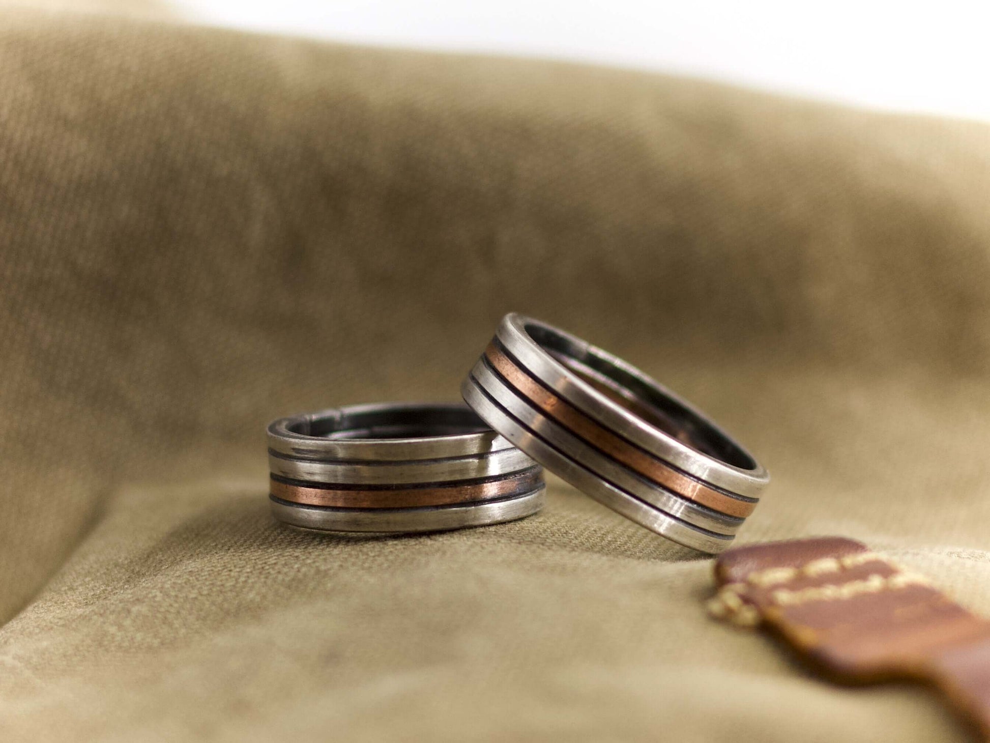 Anello a fascia artigianale uomo in metallo con dettagli di rame su sfondo beige Glimoire