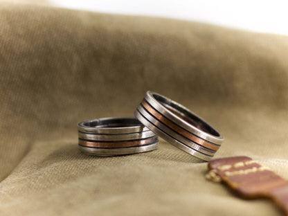 Anello a fascia artigianale uomo in metallo con dettagli di rame su sfondo beige Glimoire