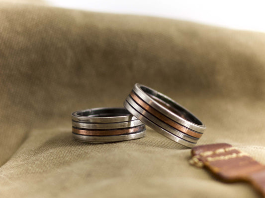 Anello a fascia artigianale uomo in metallo con dettagli di rame su sfondo beige Glimoire
