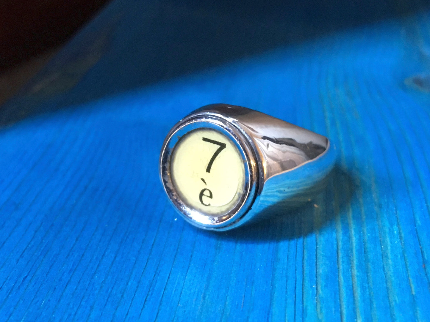 Anello a sigillo personalizzato in argento con incisione numero 7 su sfondo chiaro Glimoire