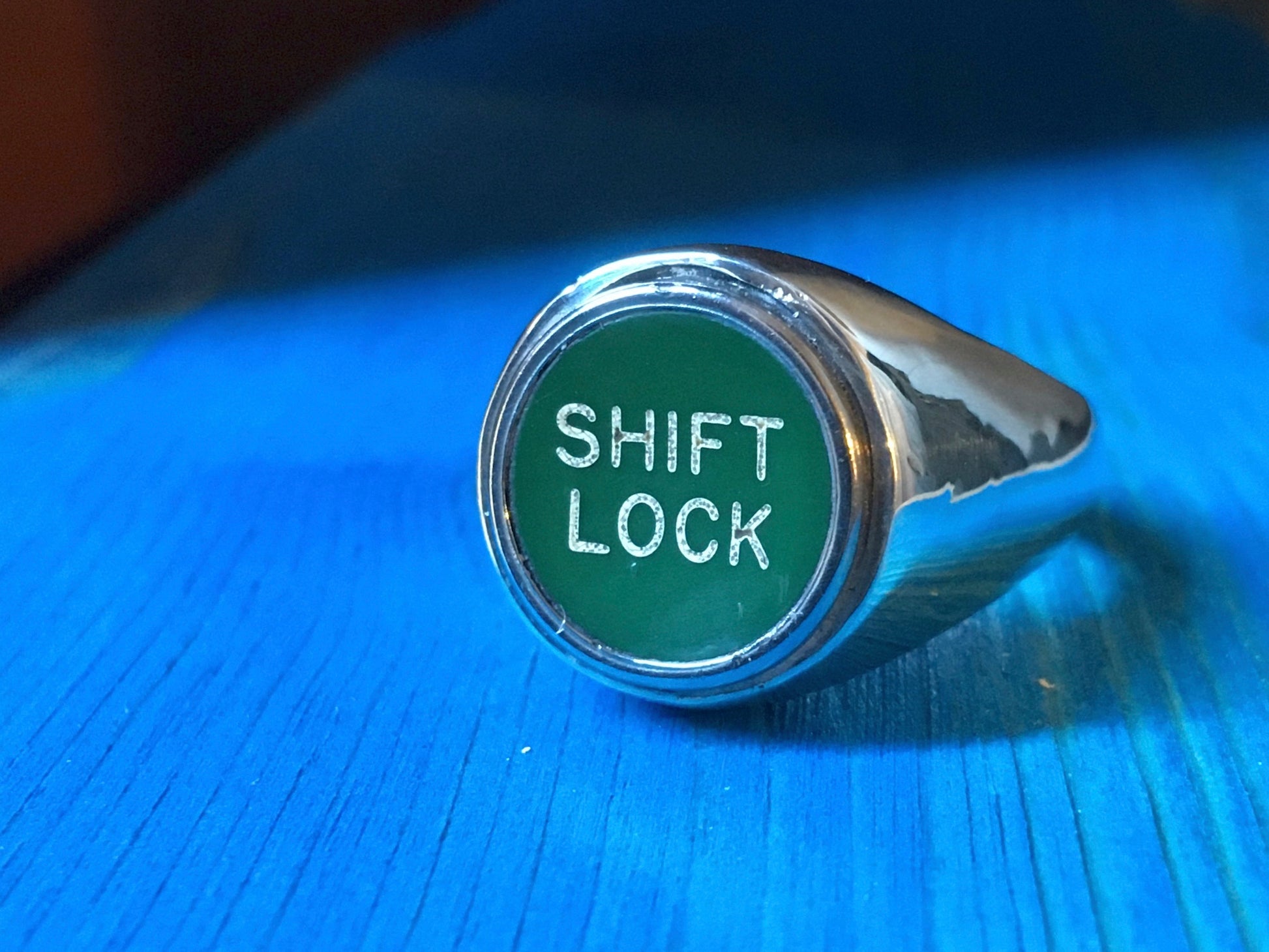 Anello a sigillo personalizzato Glimoire con scritta Shift Lock su sfondo verde e finitura argento