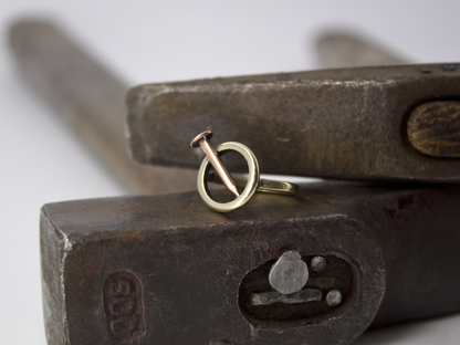 Anello chiodo di Glimoire in rame e ottone, posizionato su martello