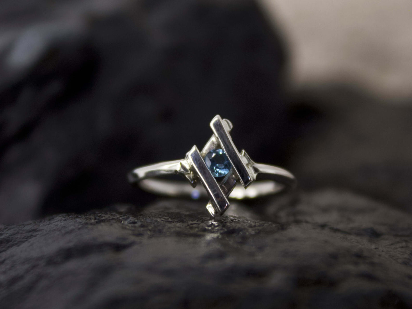 Anello in argento con pietra blu di Glimoire design moderno su superficie scura