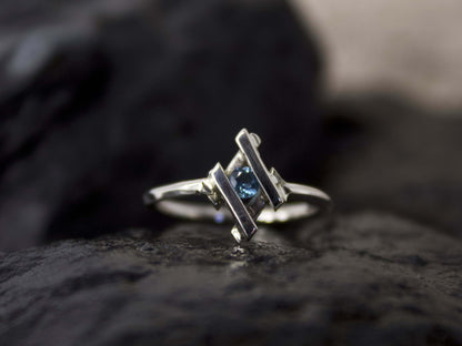 Anello in argento con pietra blu di Glimoire design moderno su superficie scura