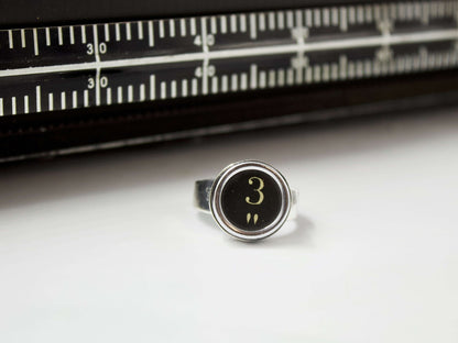 Anello in argento con tasti di macchina da scrivere vintage numero 3 su sfondo bianco