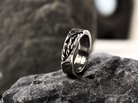 Anello intrecciato oreficeria tradizionale in argento su una base di pietra scura