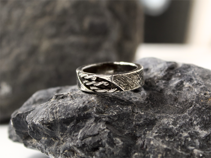 Anello intrecciato oreficeria tradizionale in argento sopra una roccia scura