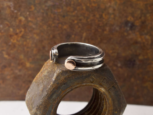 Anello maschile in argento regolabile Glimoire con design moderno posato su dado arrugginito