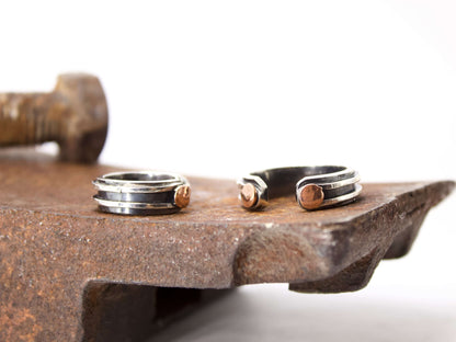 Anello maschile in argento regolabile con dettagli in rame su superficie di metallo arrugginito