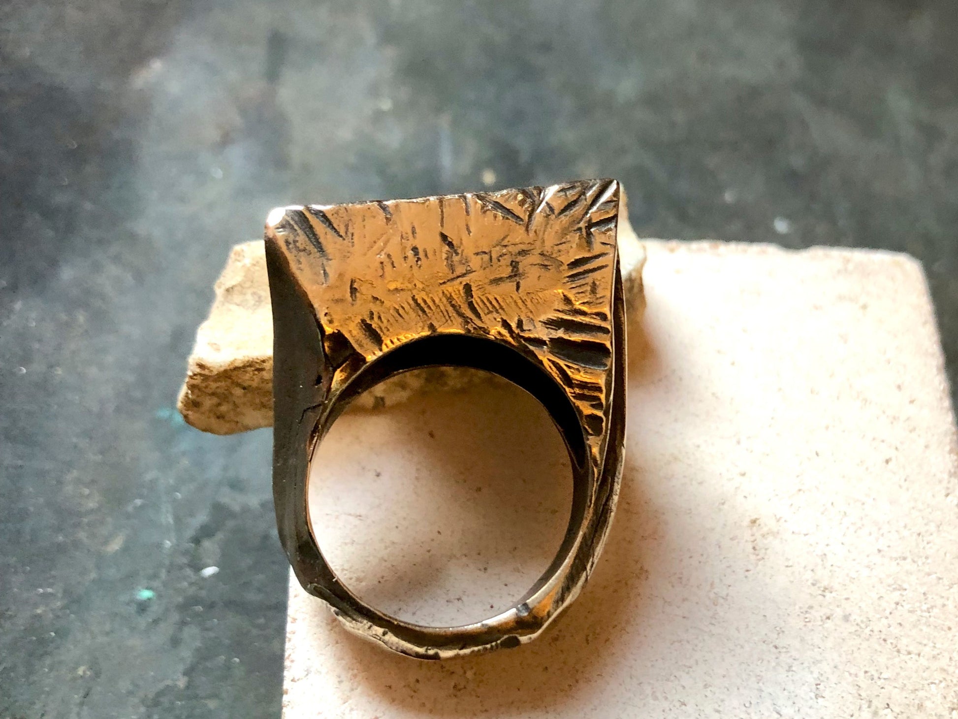 Anello materico in bronzo con finitura texture, visibile su base neutra