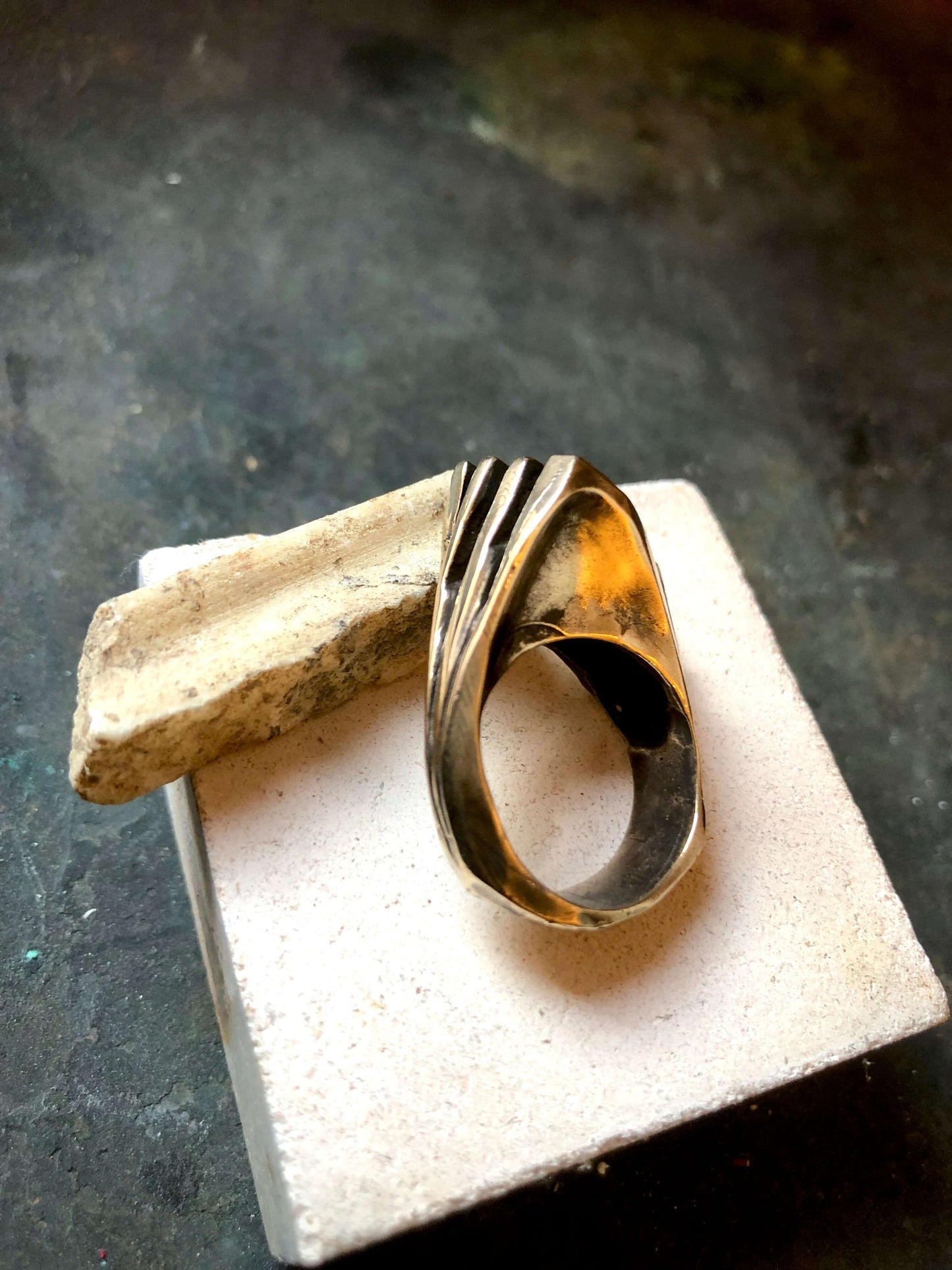 Anello materico in bronzo di Glimoire con design moderno e finitura lucida su base di pietra