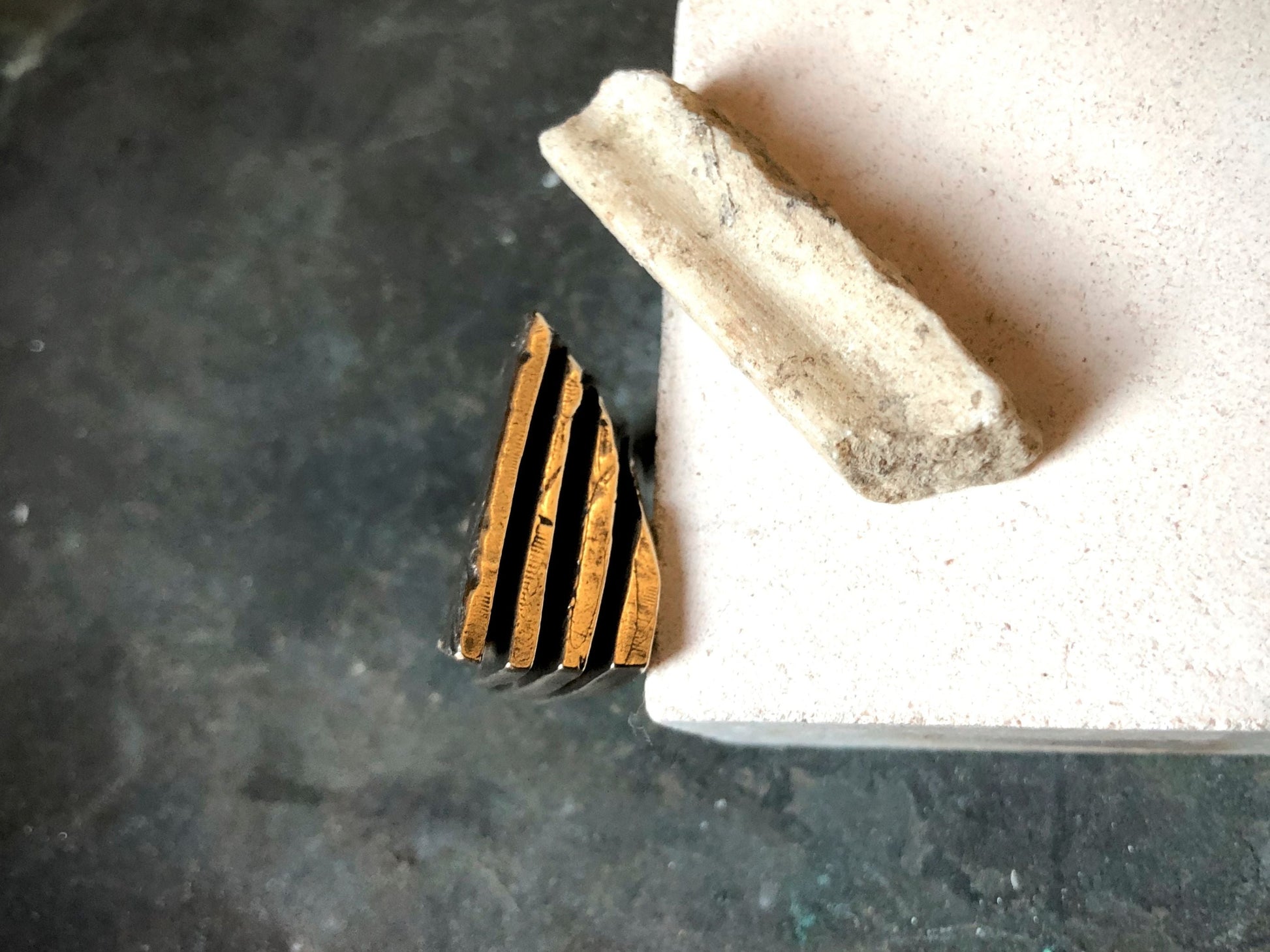 Anello materico in bronzo su base chiara con dettagli geometrico e texture unica