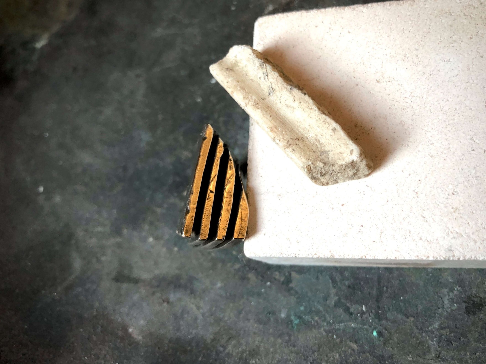 Anello materico in bronzo di Glimoire con design geometrico e finitura artigianale su sfondo scuro
