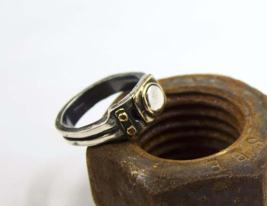 Anello stile industriale uomo Glimoire in metallo con design robusto appoggiato su grande dado arrugginito