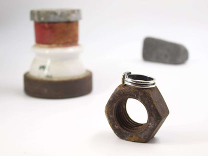 Anello stile industriale uomo Glimoire posizionato su dado di metallo arrugginito