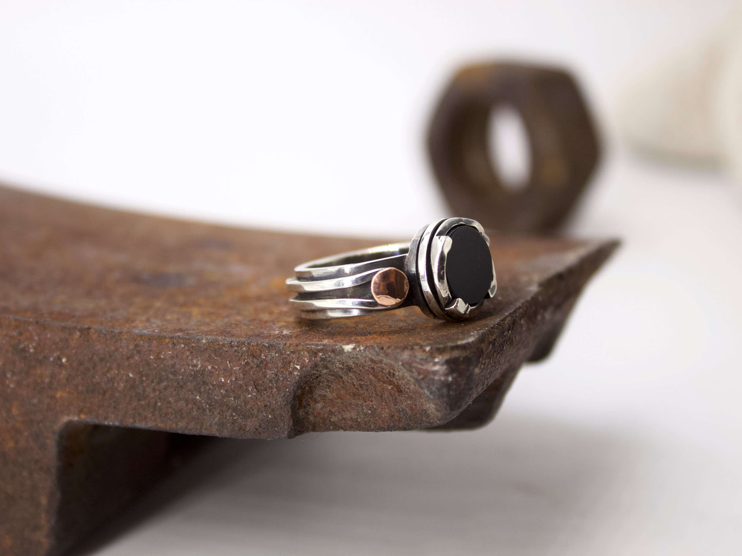 Anello da uomo in onice con design in argento e dettaglio rame su superficie arrugginita
