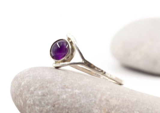 Anellino ametista Glimoire in argento con cabochon ametista tondo su sfondo di pietre naturali