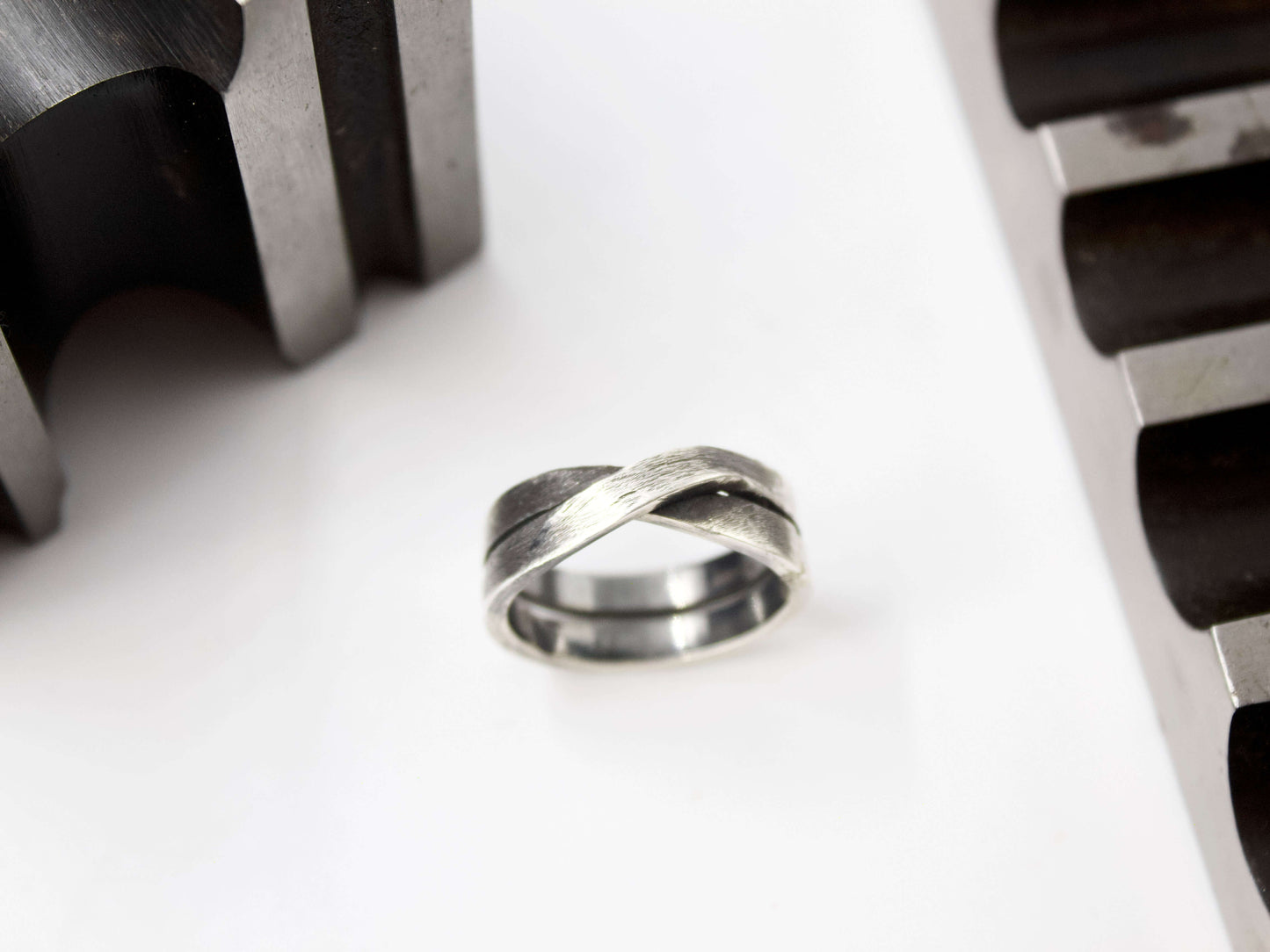 Anello maschile in argento intrecciato. Anello Glimoire su fondo bianco con dettagli meccanici