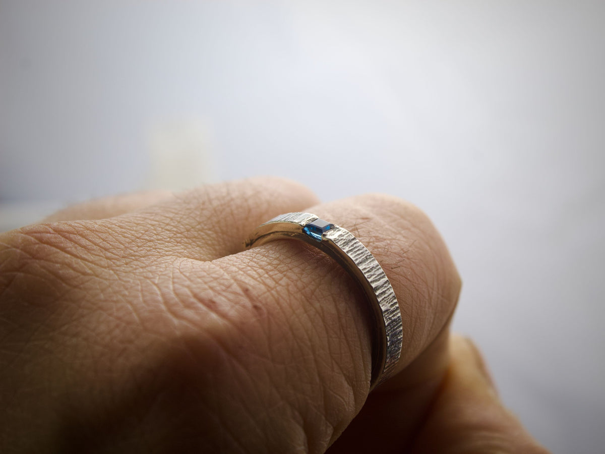 Borea anello in argento con topazio blu - martellato a taglio, indossato su un dito con texture visibile