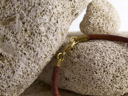 Bracciale in cuoio con dado ottone, visibile con chiusura e dettagli su superfici in pietra