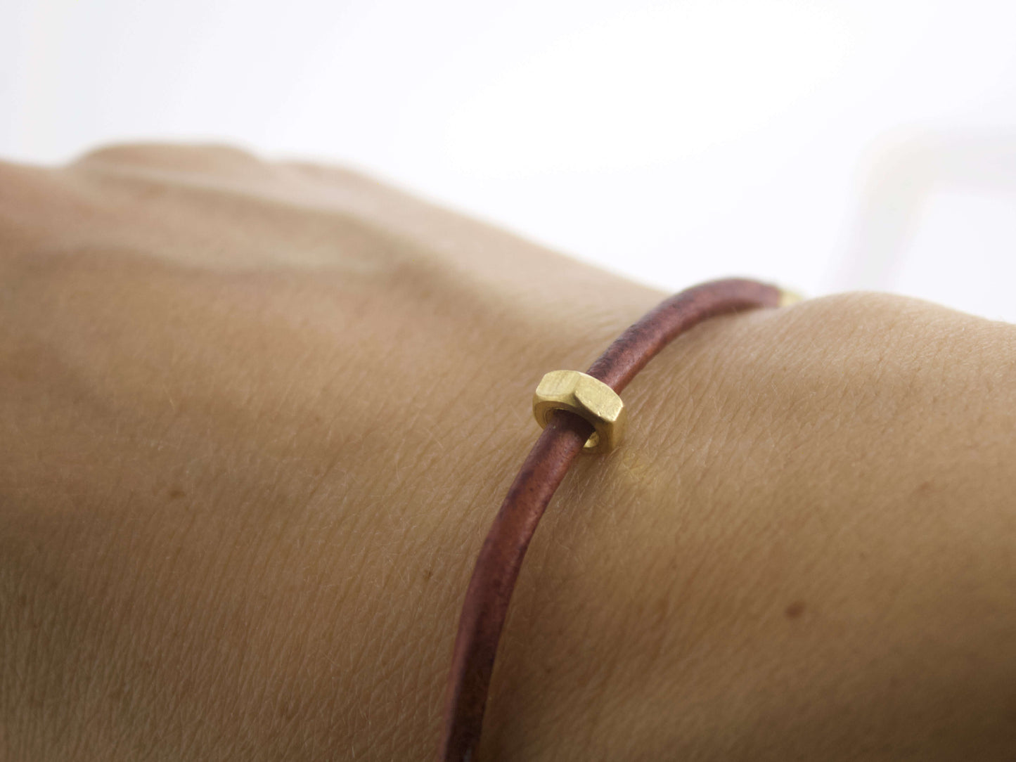 Bracciale in pelle con dado ottone indossato su un polso