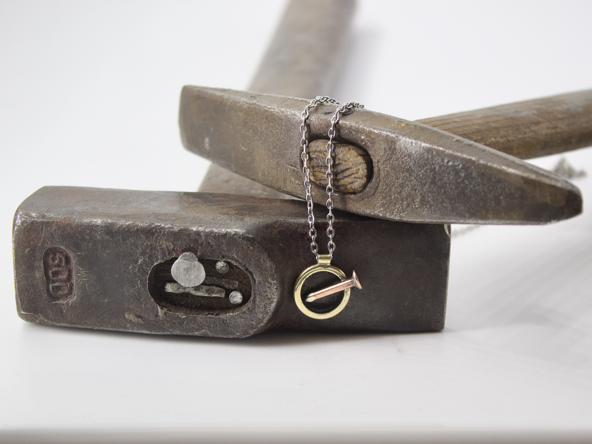 Collana chiodo con pendente che rappresenta un chiodo su un martello