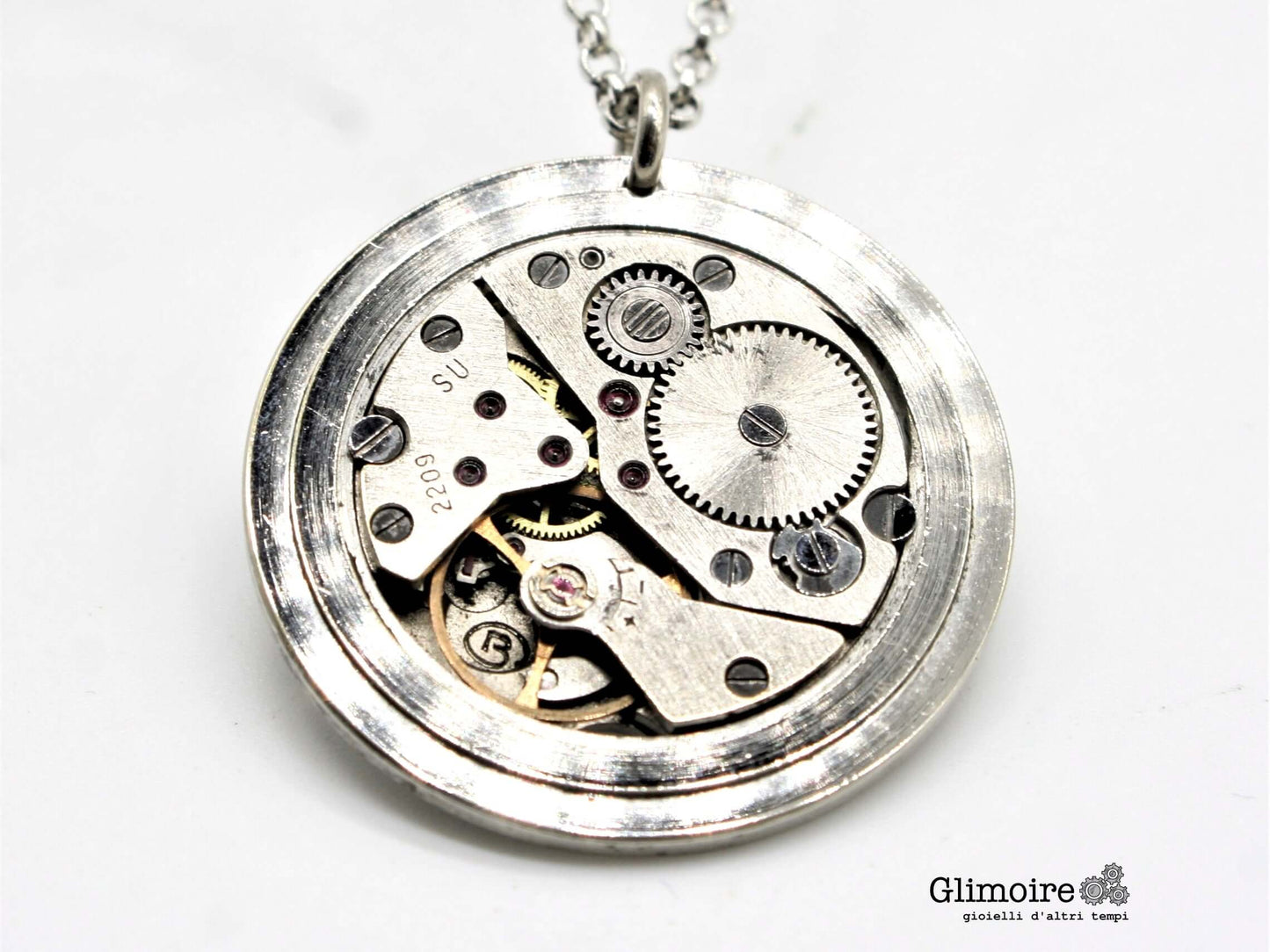 Collana Glimoire con meccanismo di orologio vintage a carica manuale, dettagli in metallo e ingranaggi visibili.