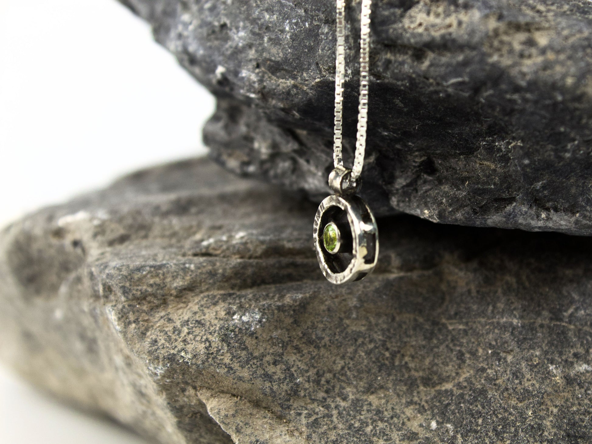 Collana Glimoire con pendente circolare in argento, con peridoto verde che sembra galleggiare al centro