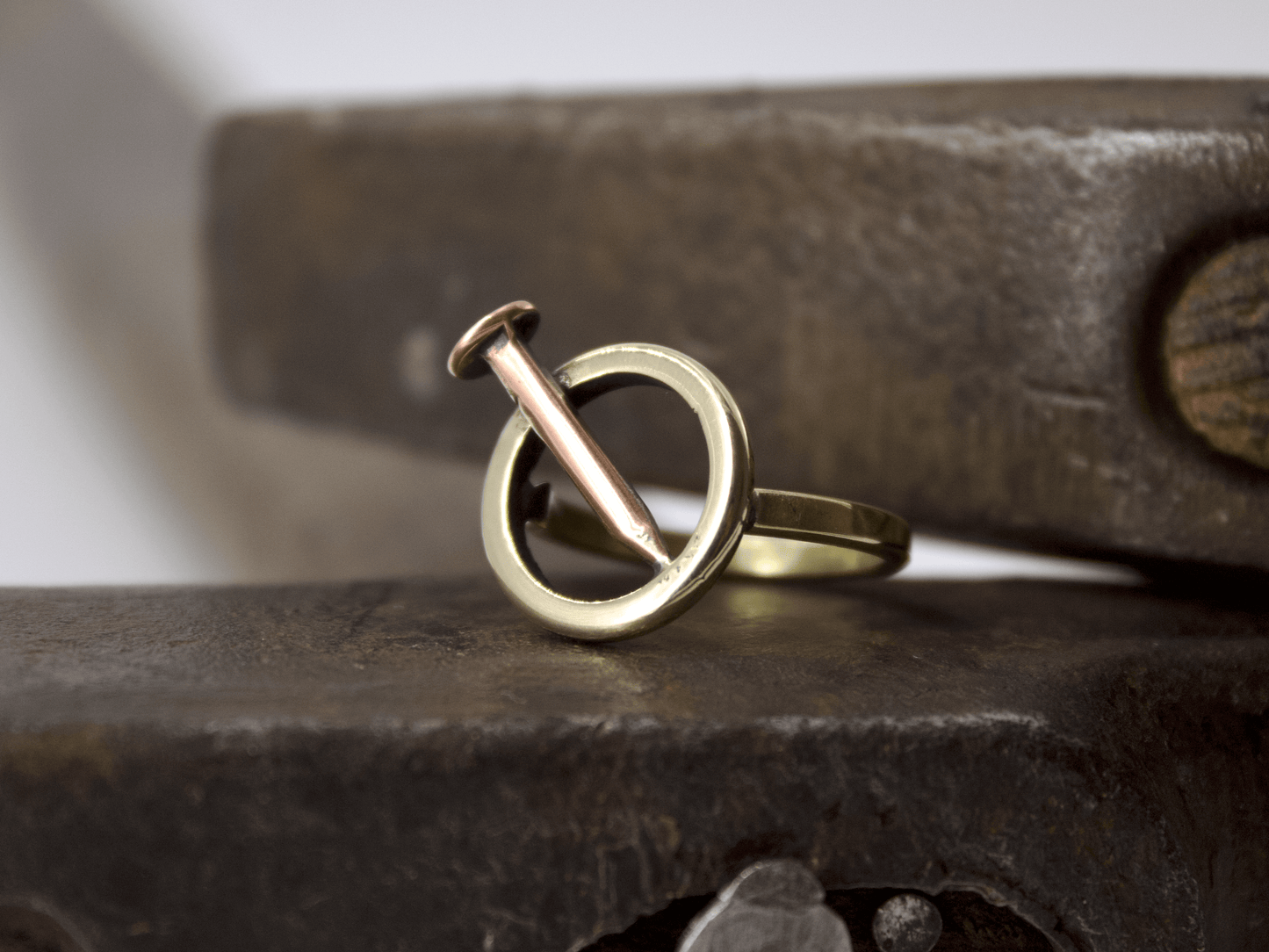 Anello chiodo Glimoire in oro e rame con design a cerchio minimalista artigianale su banco