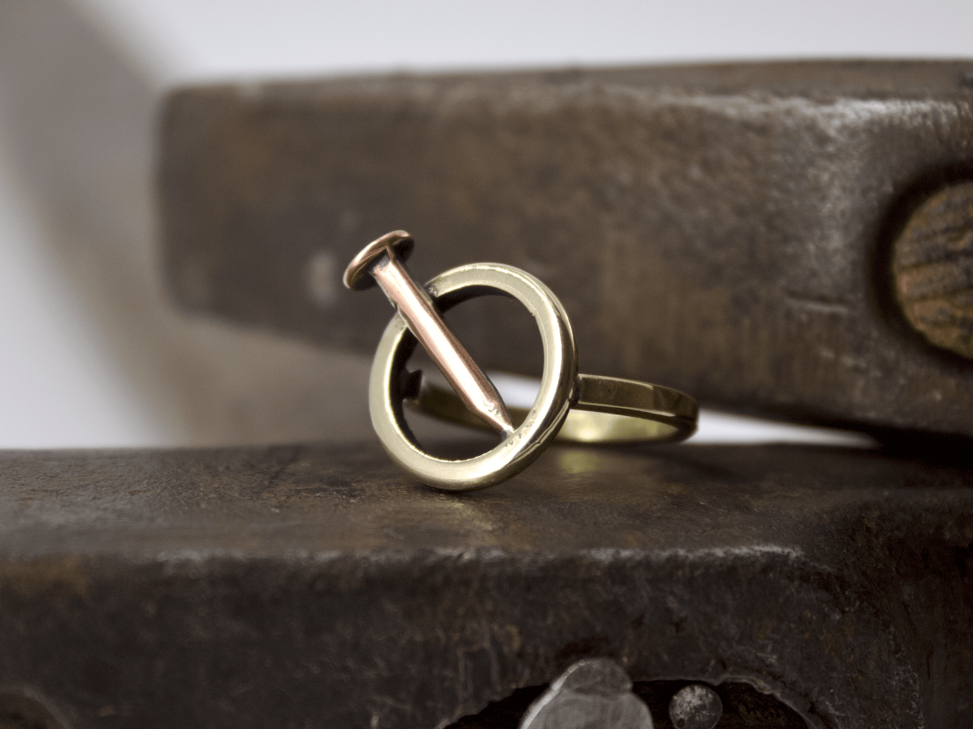 Anello chiodo Glimoire in oro e rame con design a cerchio minimalista artigianale su banco