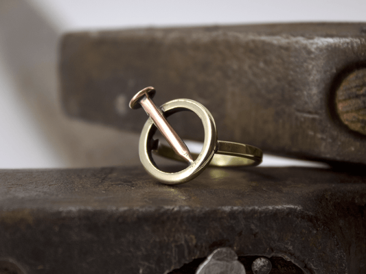 Anello chiodo Glimoire in oro e rame con design a cerchio minimalista artigianale su banco