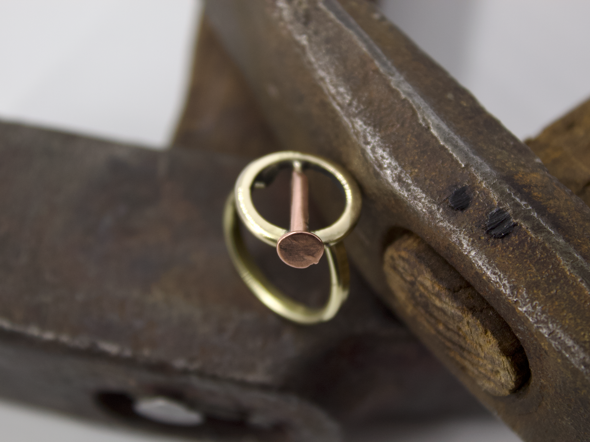 Anello chiodo Glimoire in ottone e rame con design chiodo minimal posato su attrezzo metallico