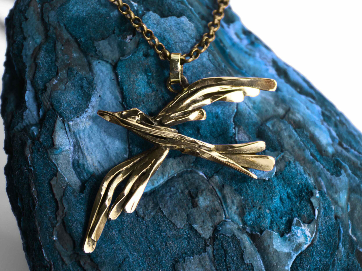 Collana  fenice in bronzo fatta a mano, elegante e artigianale, su sfondo blu