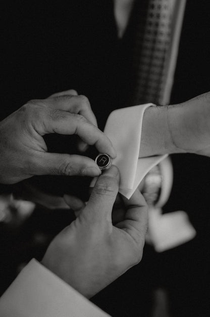 Uomo elegante che sistema Gemelli in argento con iniziali . Glimoire gemelli da camicia tondi neri con incisione