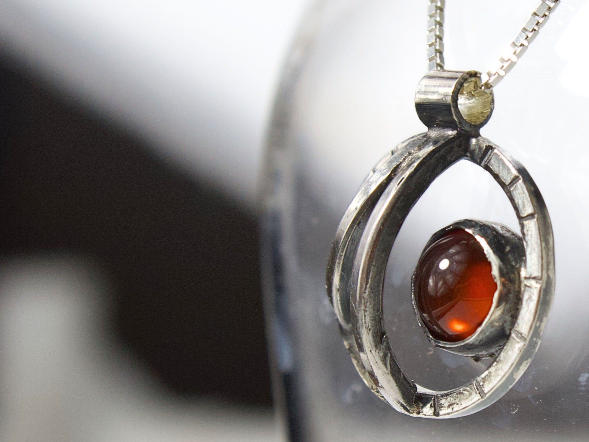 Collana Orbite con pietra rossa in pendente su sfondo elegante