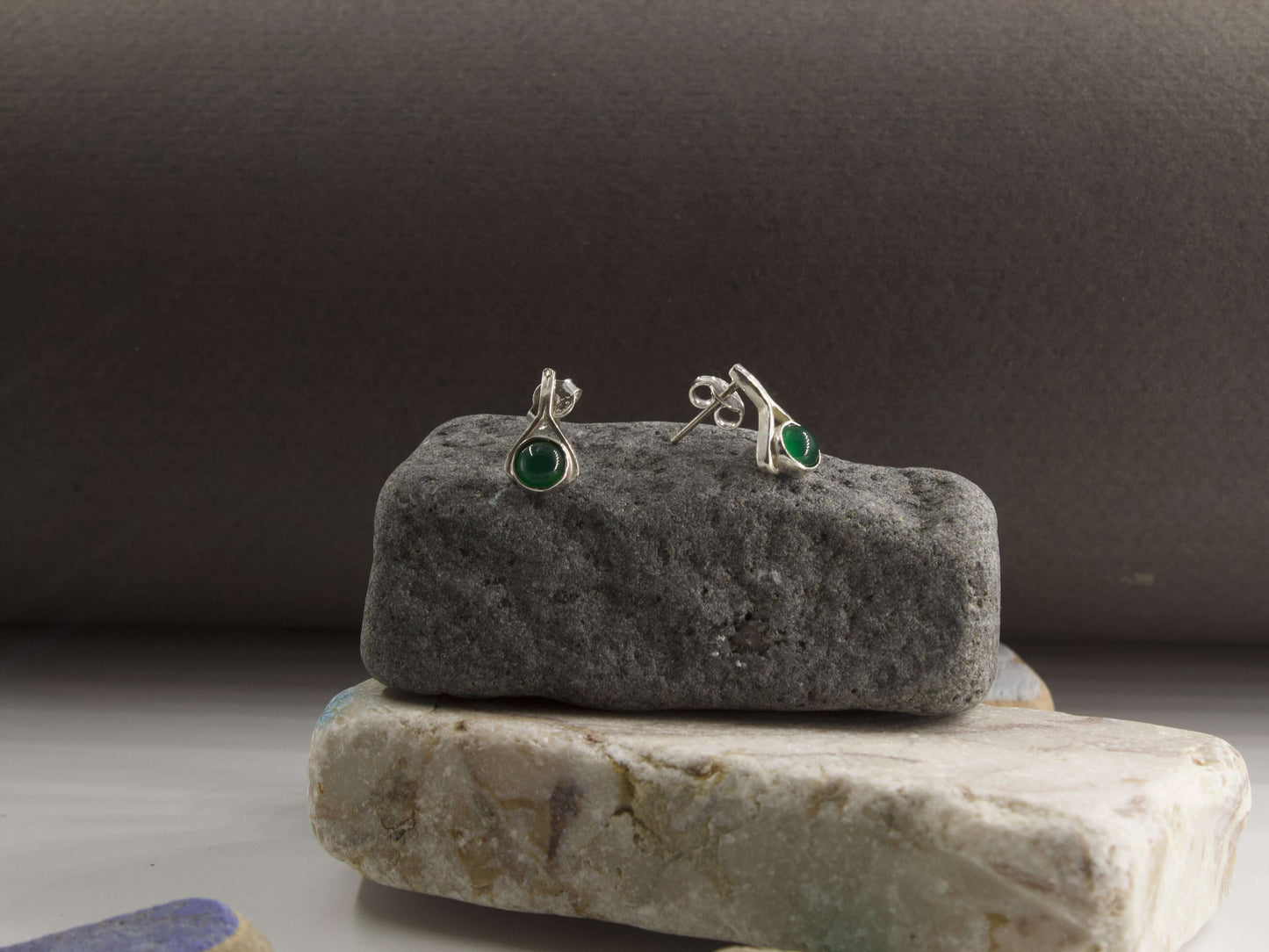 Orecchini a goccia con pietre colorate in argento su una base di pietra grigia